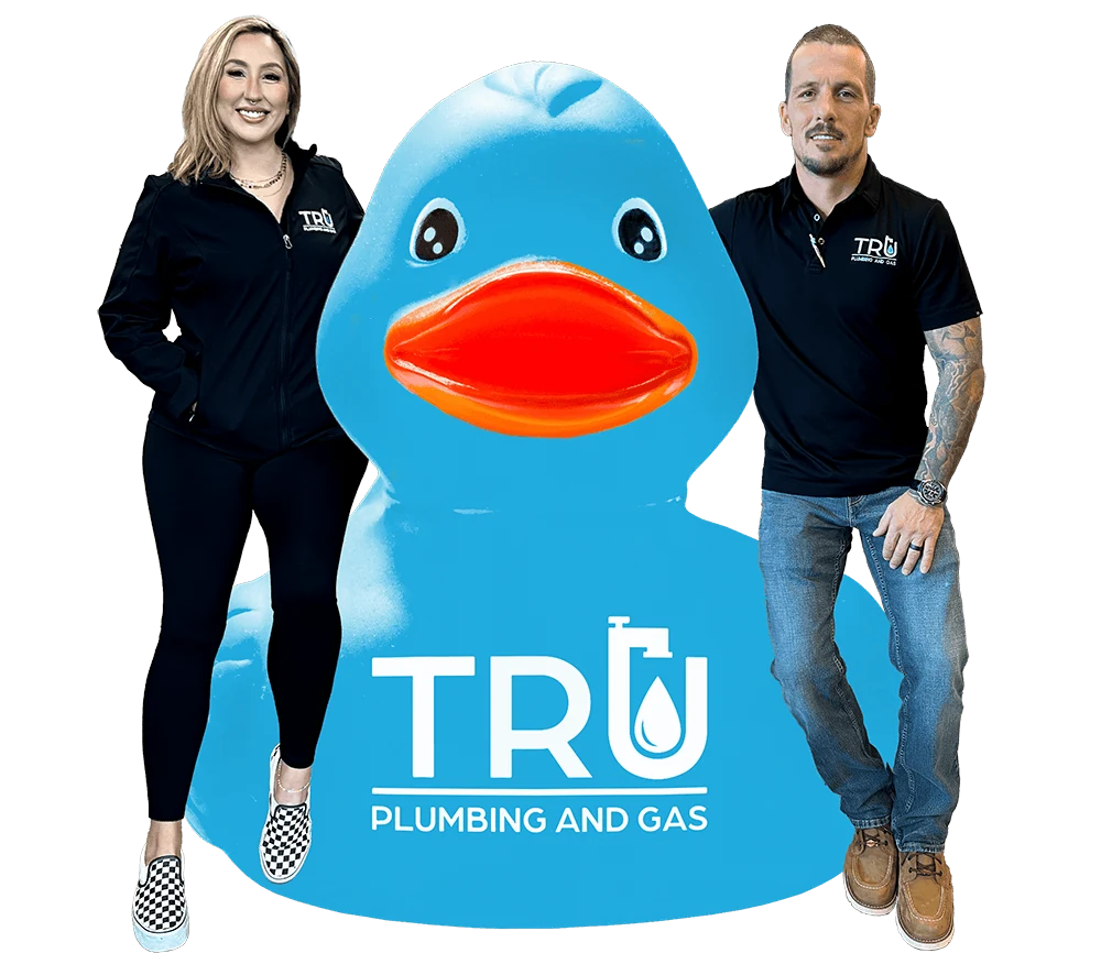Two members of the Tru Plumbing and Gas team standing beside the Tru rubber duck mascot