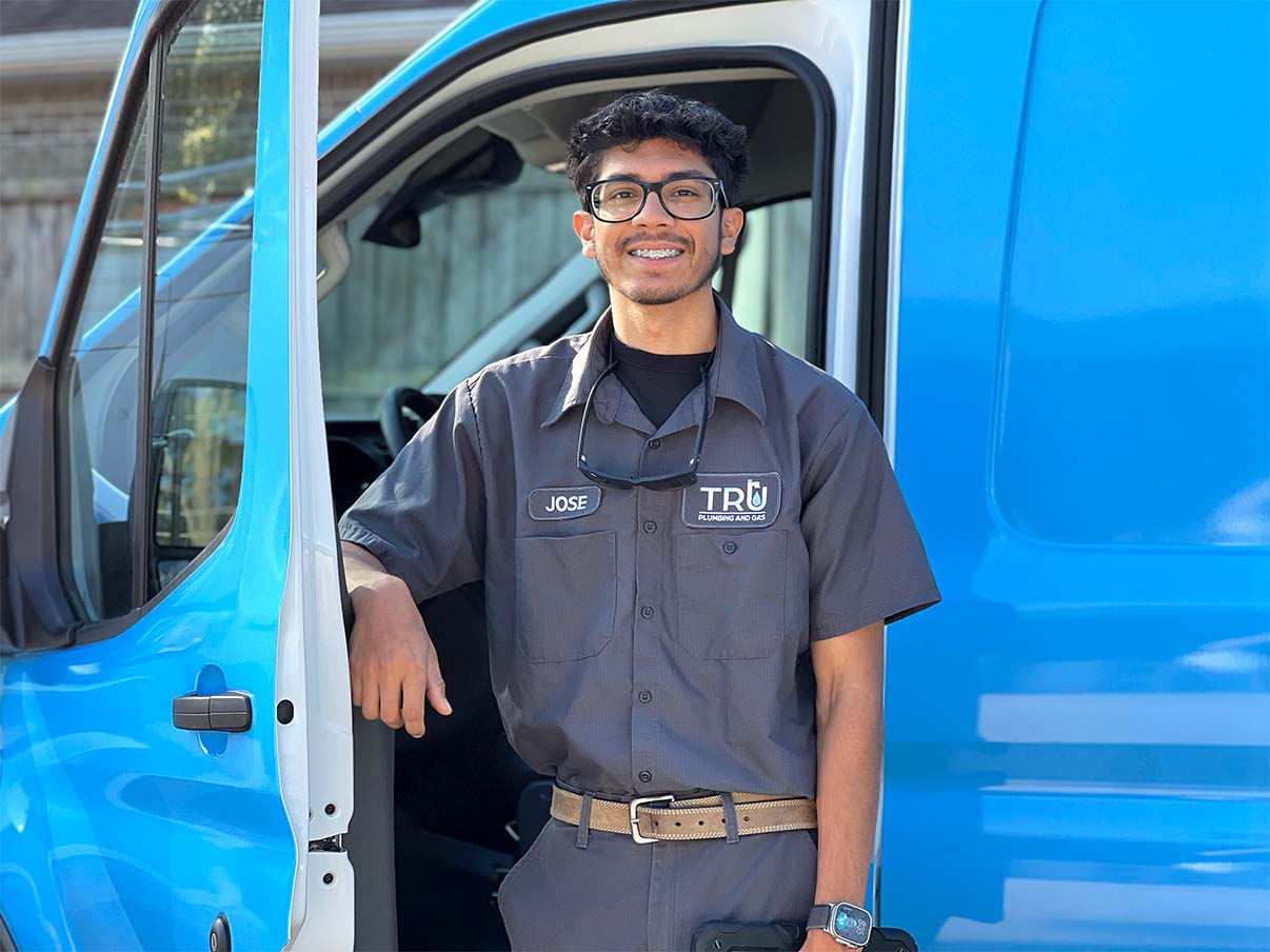 Smiling Niceville plumber in uniform standing outside Tru Plumbing and Gas van