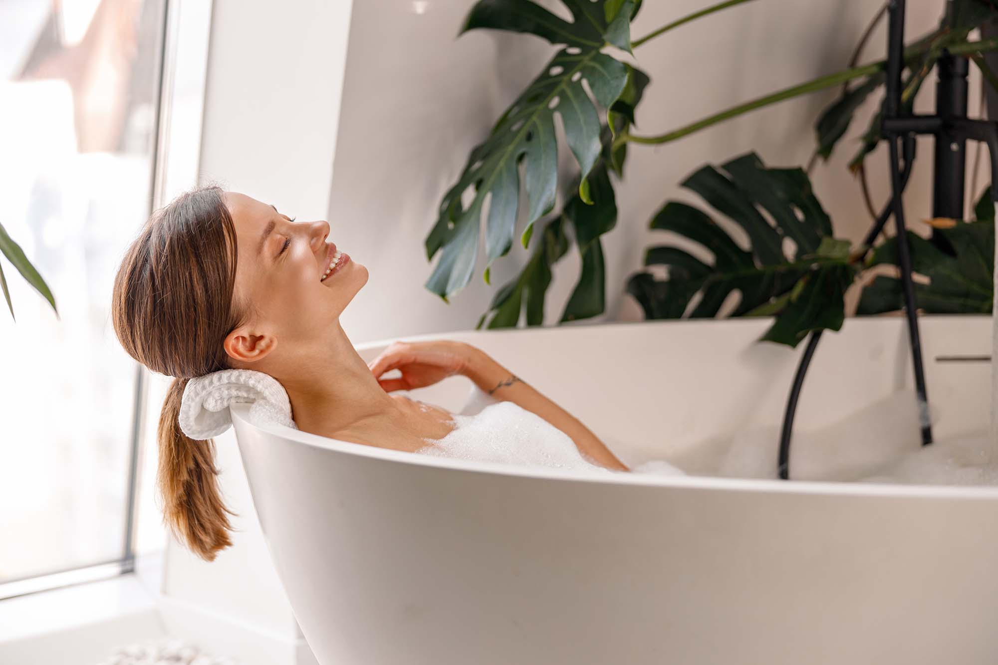 Relaxed woman leaning back and smiling in bathtub