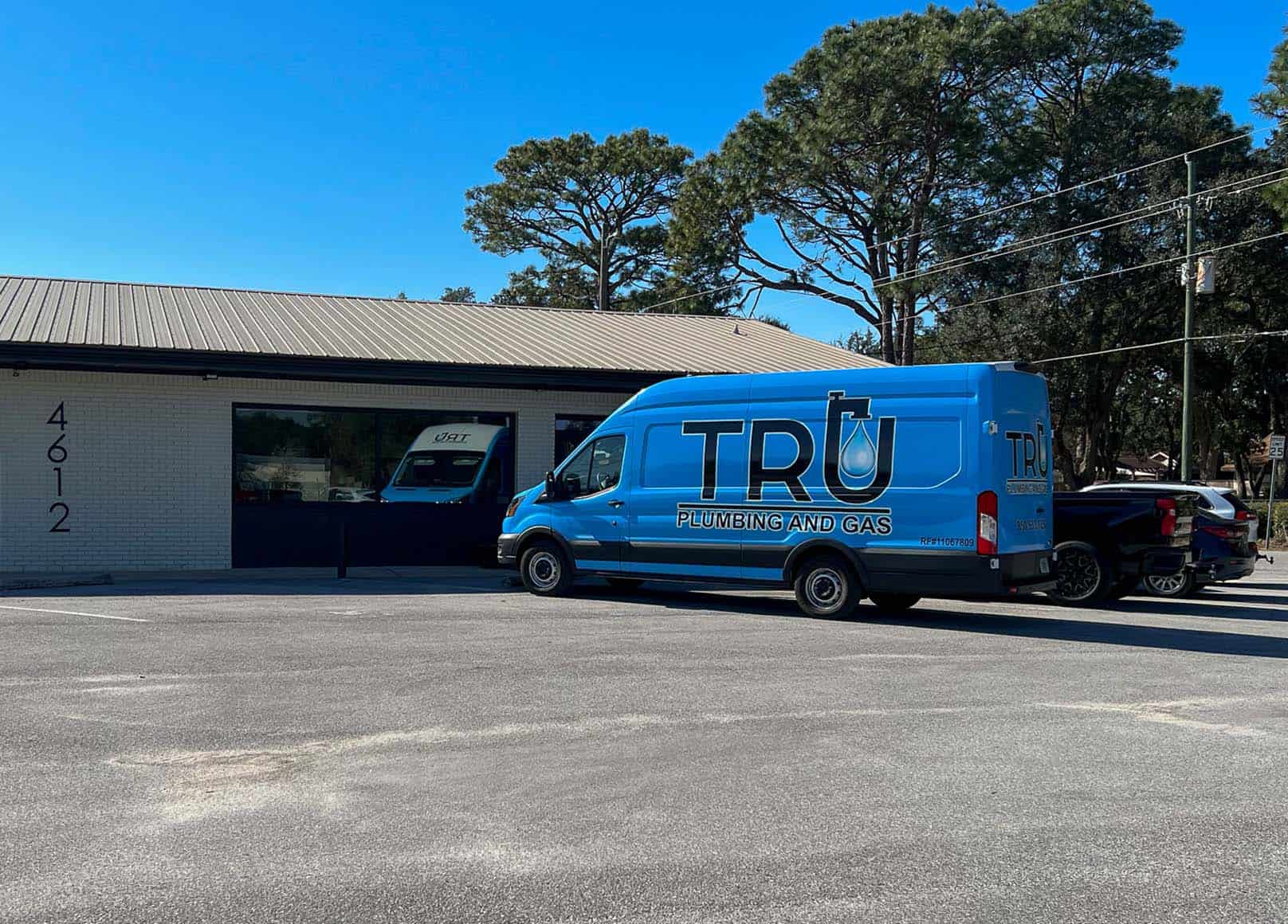 Bright blue van with our logo outside our office, an off-white brick building